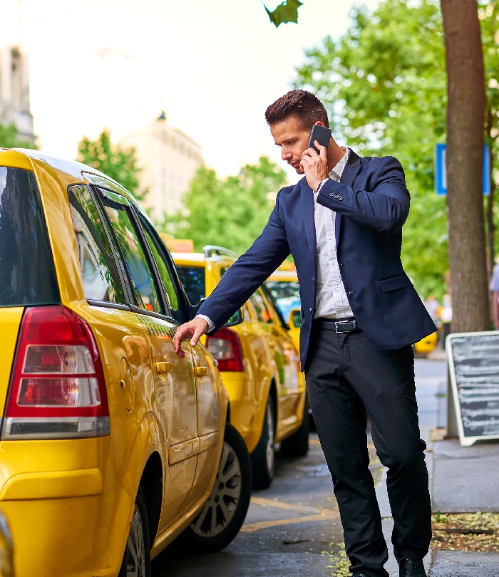 Chauffeur de taxi ouvrant la porte d’un véhicule jaune lors d’un trajet professionnel.