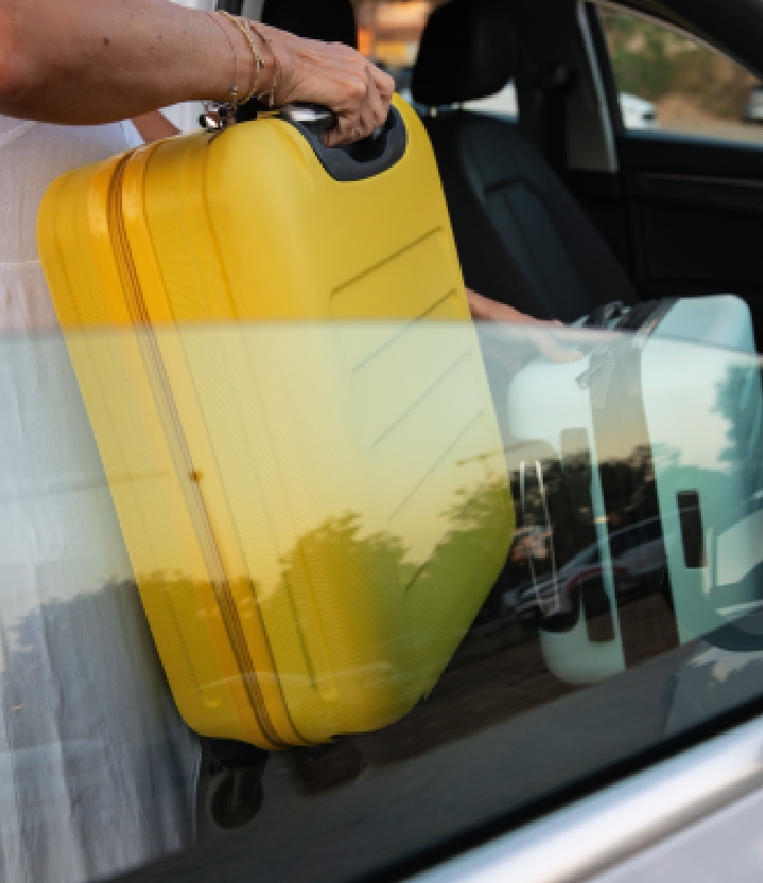 Valise jaune chargée dans un taxi pour un transfert gare ou aéroport.